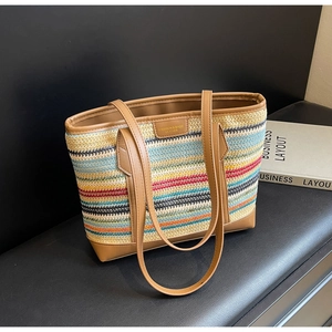 Detailed shot of multi-colored woven straw tote bag with brown leather handles and gold logo