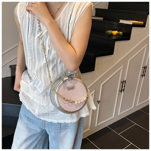 Detail of round crossbody bag with pink woven texture, gold chain and pearl accents