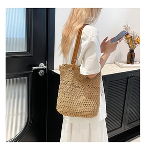 Detailed close-up of handmade woven straw tote with brown faux leather straps and wavy trim