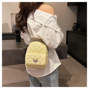 Close-up of yellow quilted leather mini backpack with silver chain and metal turn-lock