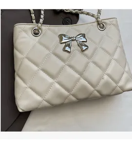 Detail of beige quilted leather shoulder bag with silver bow and chain strap