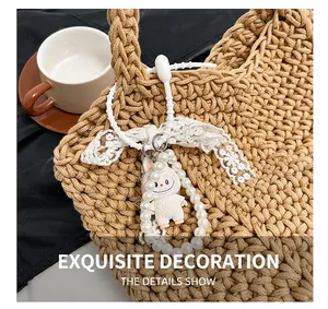 Close-up of a Labubu plush doll bag charm with pearls and lace on a woven tote