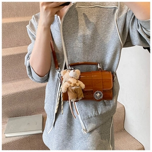Detail of caramel brown patent leather mini bag with cute teddy bear bag charm