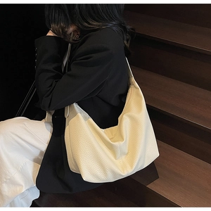 Detail of off-white lychee pattern leather texture on a minimalist large shoulder bag
