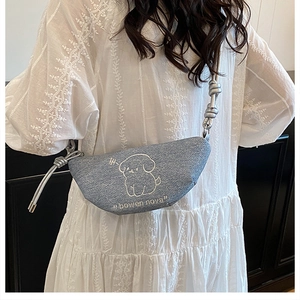 Détail du sac croissant en denim bleu clair avec broderie chiot blanc et bandoulière en corde