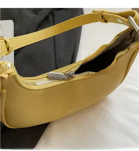 Detail of a bright yellow crescent bag with lychee texture and smooth silver zipper