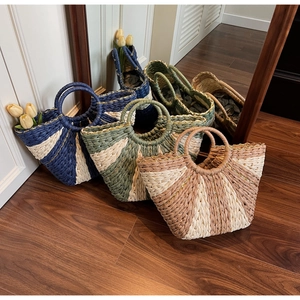 Detail of multi-color woven straw bags with round handles and metallic gold thread