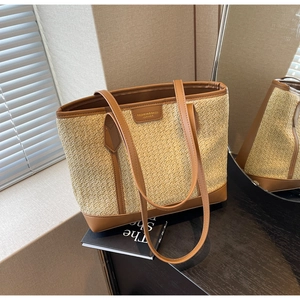 Detail of woven straw tote bag with brown leather trim and fashion leather patch