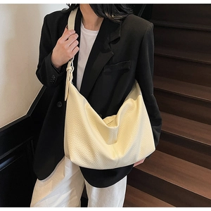 Detail of minimalist cream leather hobo bag with pebble texture and slouchy design