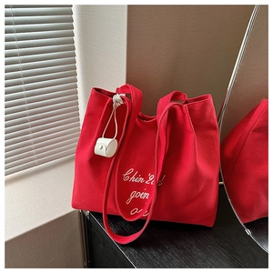 Détail du sac cabas en toile rouge avec lettrage blanc et mini accessoire sur la sangle