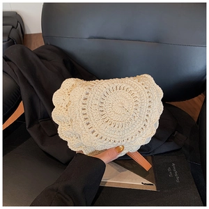 Detail of handwoven cream crochet saddle bag with petal edge and brown leather zipper pull