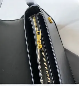 Détail de la fermeture éclair dorée et de l'intérieur en cuir noir du sac à bandoulière