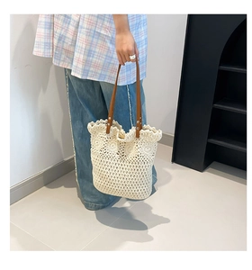 Detail of hand-woven off-white tote bag with floral crochet pattern and brown leather handles