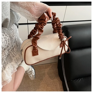 Dettaglio della trama in tela beige con manici in pelle marrone della borsa Boston
