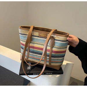 Close-up of colorful striped woven tote bag with brown leather handles and brand tag