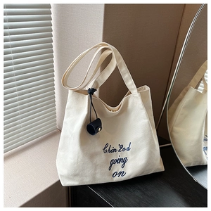 Détail du sac cabas en toile avec broderie bleue et fermeture magnétique sur bois