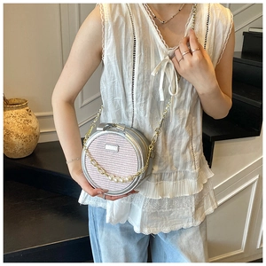 Detail view of the silver crossbody bag with large white pearls and a golden chain strap