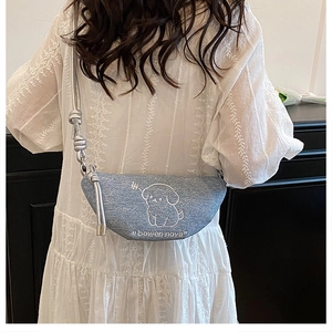 Détail du sac demi-lune en jean bleu clair avec broderie chien blanc et bandoulière