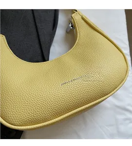 Close-up of yellow crescent shoulder bag featuring premium litchi grain leather texture