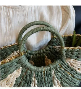 Macro detail of hand-woven straw bag featuring green and beige fibers with gold tinsel accents