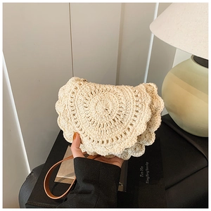 Close-up of cream crochet saddle bag with scalloped edges and brown leather strap