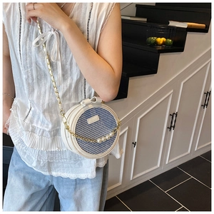 Detail of blue and white checkered mini round bag with pearl chain and bow decoration