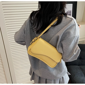 Detailed view of a yellow lychee leather shoulder bag worn by a model in casual attire