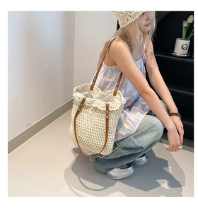 Close-up of cream woven straw tote bag featuring wavy edges and brown leather straps