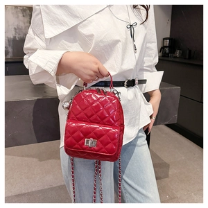 Detail of red quilted patent leather backpack with silver twist lock and chain strap