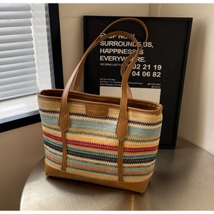 Macro detail of colorful woven tote bag with brown leather handles and brand logo tag