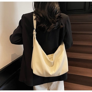 Rear view of model wearing a beige oversized crescent hobo bag with wide strap