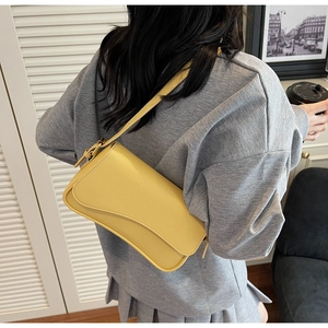 Detail of yellow lychee pattern leather shoulder bag with adjustable strap worn by model