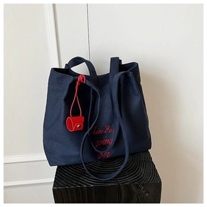 Détail du sac cabas en toile bleu marine avec broderie rouge et mini pochette assortie