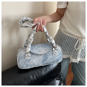 Dettaglio borsa a bauletto in denim con tessuto lavato blu e manico metallico argento