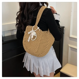 Detail of khaki woven tote bag with pearl chain, lace bow and cute animal charm accessories