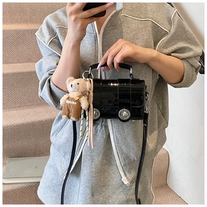 Detail of black patent leather car-shaped handbag with teddy bear charm and silver hardware