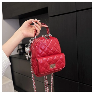 Detail of red quilted patent leather mini backpack with silver clasp and dog charm