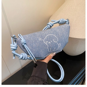 Détail du sac demi-lune en jean bleu clair avec broderie chien de dessin animé et bandoulière