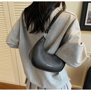 Detail of black pebbled leather crescent bag with adjustable strap and silver metal hardware