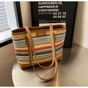 Detail of colorful woven tote bag featuring striped straw texture and brown leather handles