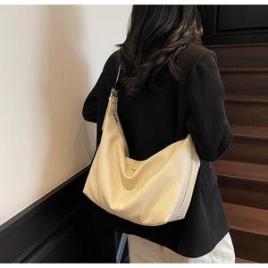 Detail of off-white lychee grain leather shoulder bag worn on a vintage wooden staircase