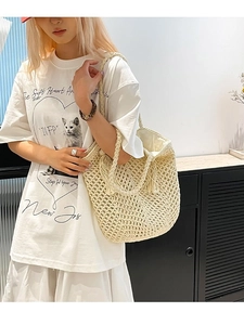 Cream woven hollow tote bag with tassels shown on shoulder for beach vacation style