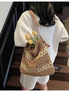 Woven straw tote bag with cutout flower patterns and a colorful patterned shoulder strap