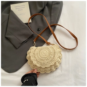 Detail of hand-woven beige knit saddle bag with brown leather strap and wavy crochet texture