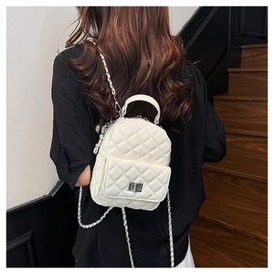 Close-up of white quilted mini backpack featuring silver chain straps and metal turn-lock