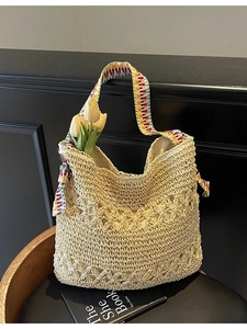 Chic cream woven shoulder bag with colorful embroidered strap on dark furniture