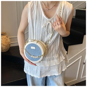 Blue and white woven round crossbody bag with gold chain and large pearl accents