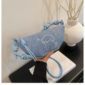 Détail du sac croissant en denim bleu clair avec broderie chiot et bandoulière nouée