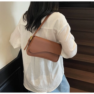 Brown litchi texture leather underarm bag with irregular curved flap and golden buckle