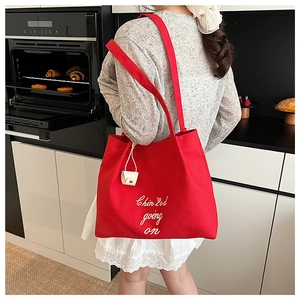 Détail du sac cabas en toile rouge avec broderie blanche et pochette assortie à clipser